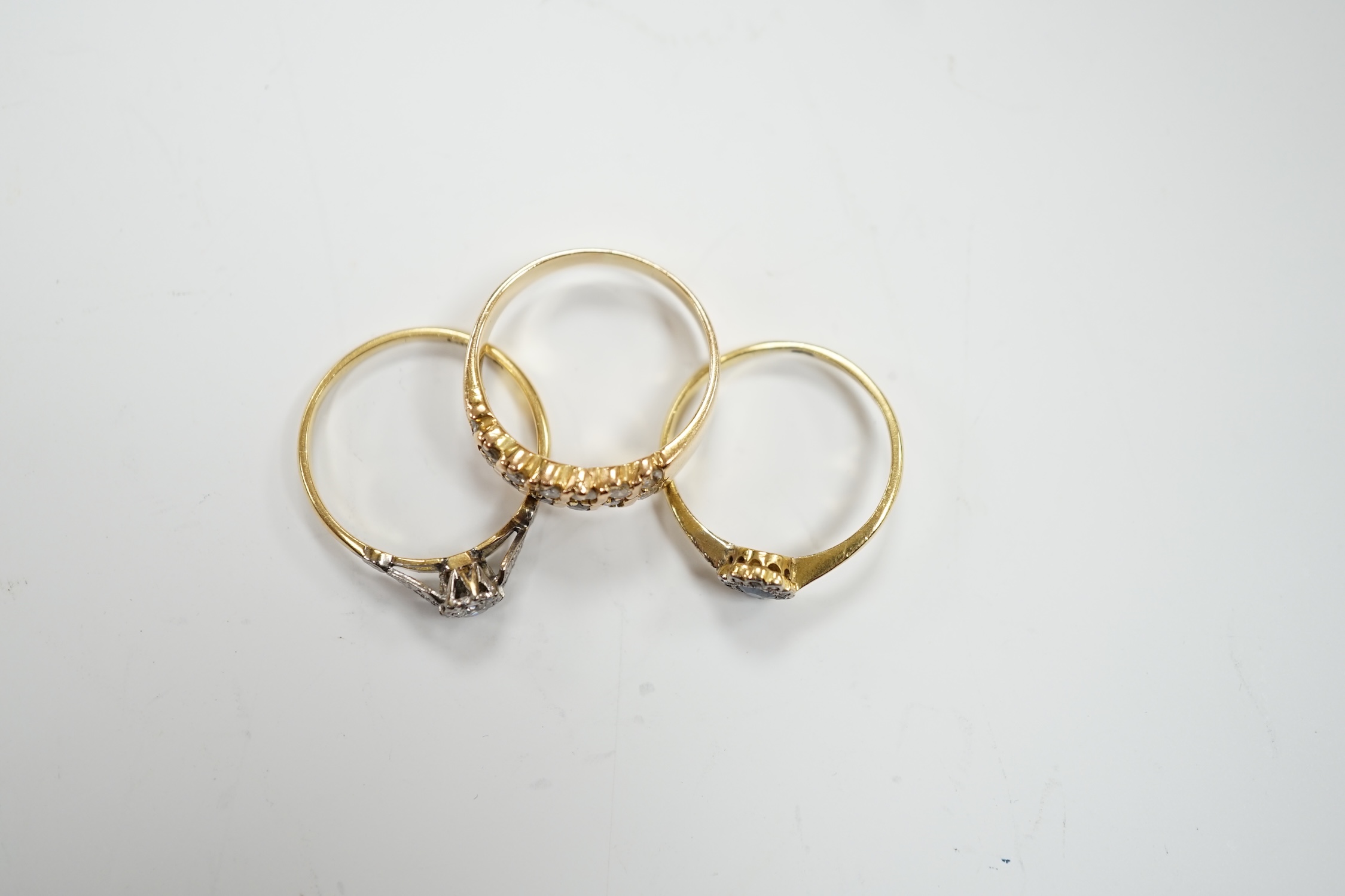 Three assorted yellow metal and gem set rings including an 18ct, plat and illusion set solitaire diamond ring, size Q, gross weight 8.1 grams.